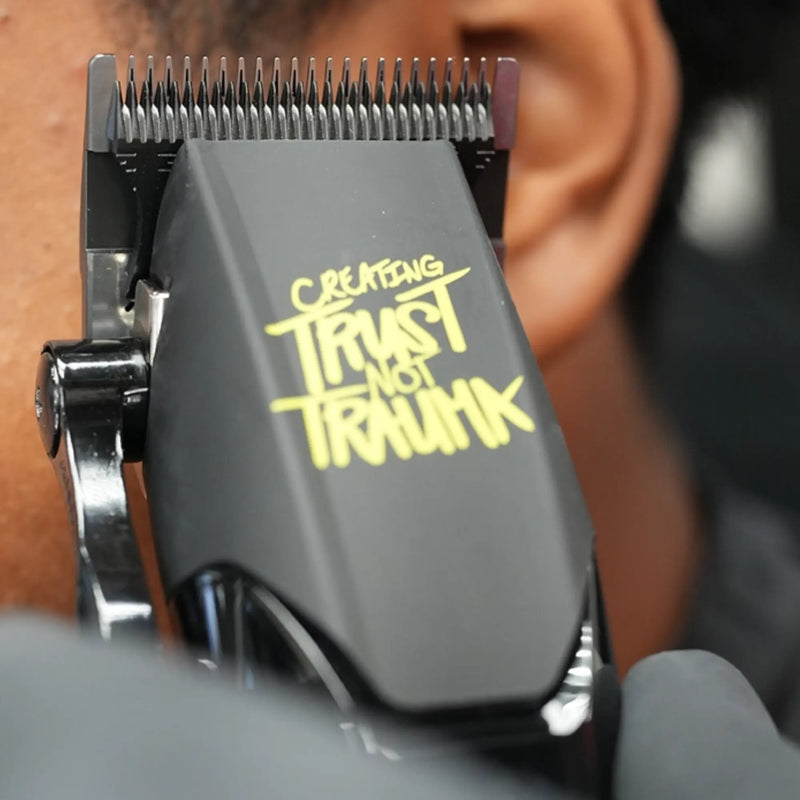 Hair Clipper with 'Creating Trust Not Trauma' text held by a person.