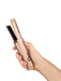Hand holding a rose gold hair straightener on a white background