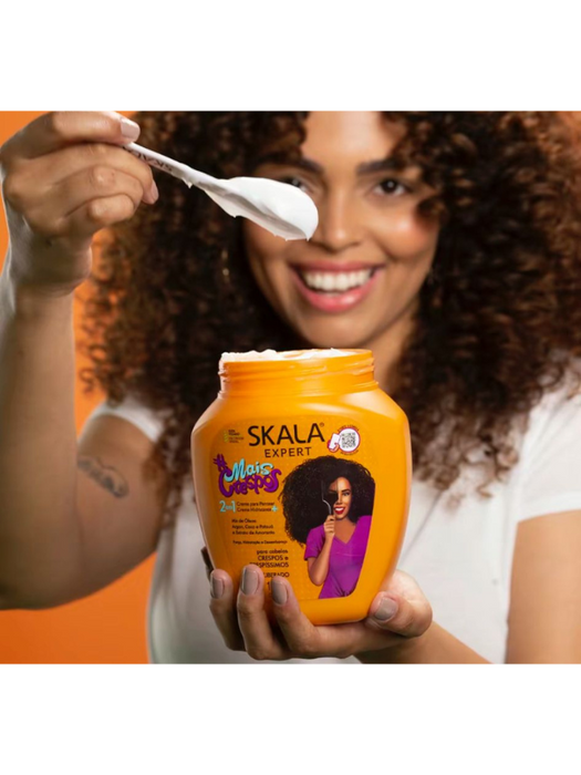 Woman holding a Skala hair care product with a spoon, against an orange background