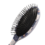 Hairbrush with black bristles and a patterned handle on a white background