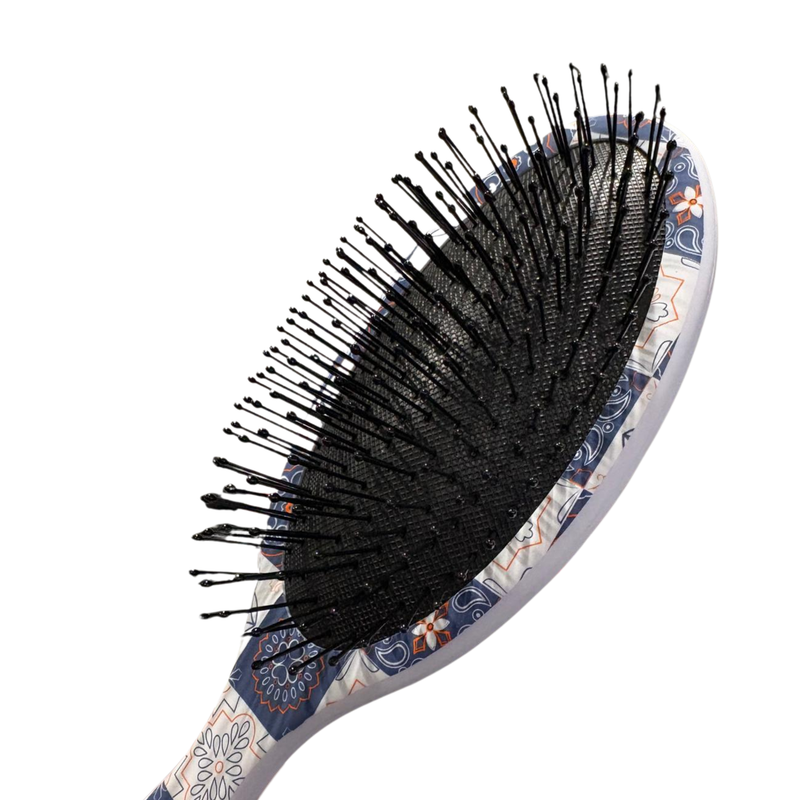 Hairbrush with black bristles and a patterned handle on a white background