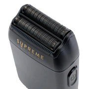 Black electric shaver with 'Supreme' branding on a white background showing shaver foils