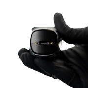 Black electronic device held by a gloved hand showing USB-C on a white background