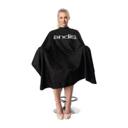 Person wearing a black 'andis' hairdressing cape on a white background