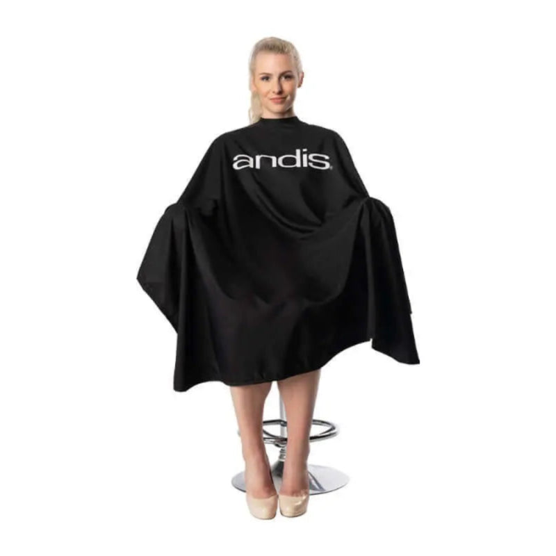 Person wearing a black 'andis' hairdressing cape on a white background