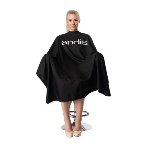 Person wearing a black 'andis' hairdressing cape on a white background