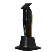 Black cordless electric hair clippers with a gold accent on the handle, shown standing upright on a matching black charging dock against a plain white background.