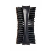 A close-up of a black grooming brush with a textured black handle and dense black bristles, shown against a plain white background.