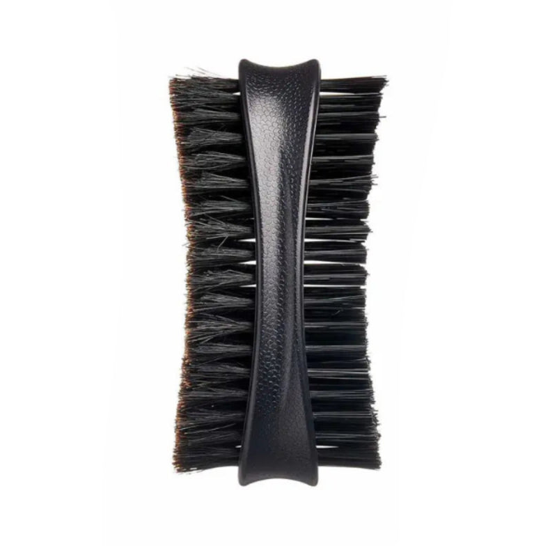 A close-up of a black grooming brush with a textured black handle and dense black bristles, shown against a plain white background.